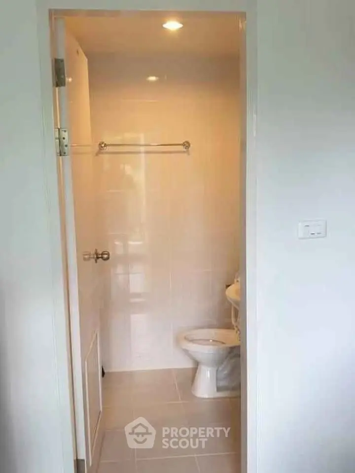 Compact bathroom with white tiles and modern fixtures in a cozy apartment.