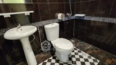 Modern bathroom with stylish dark tiles and geometric floor design.