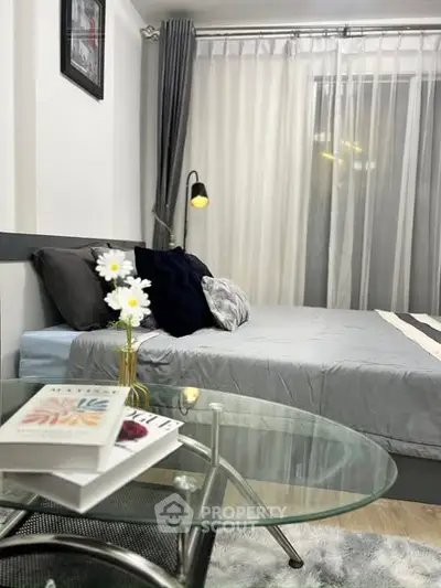 Cozy bedroom with modern decor and glass table, perfect for relaxation.