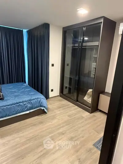 Modern bedroom with sleek wardrobe and elegant blue curtains