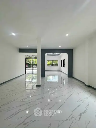 Spacious modern living room with marble flooring and large windows for natural light.