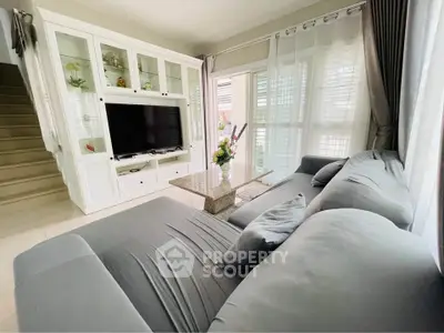 Spacious living room with modern gray sofa and large TV unit, perfect for relaxation.