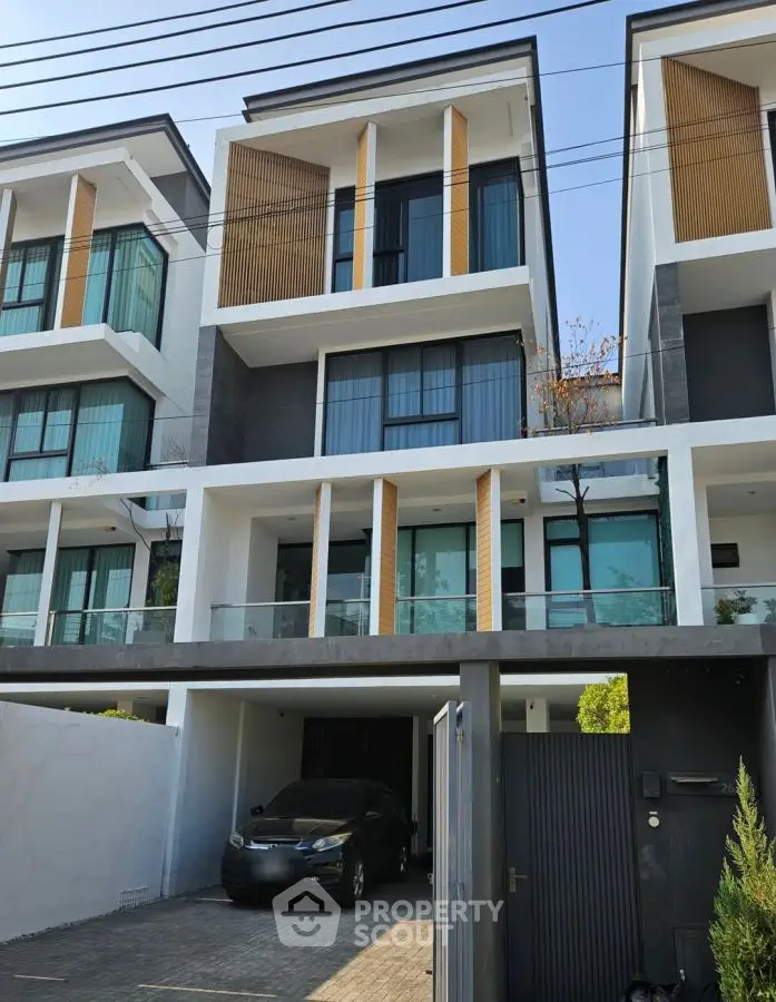 Modern three-story townhouse with sleek design and spacious garage in urban setting.