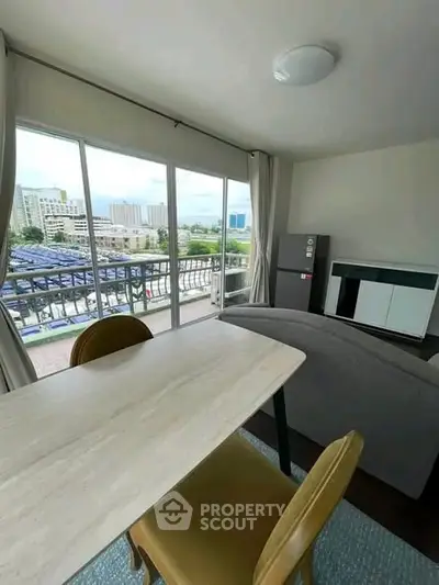 Modern living room with large windows and city view, featuring stylish furniture and natural light.