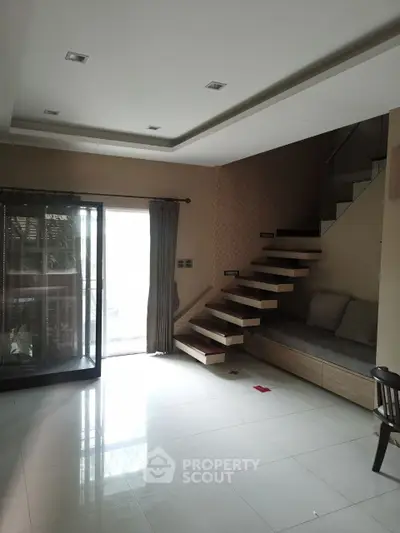 Modern living room with floating staircase and large window for natural light