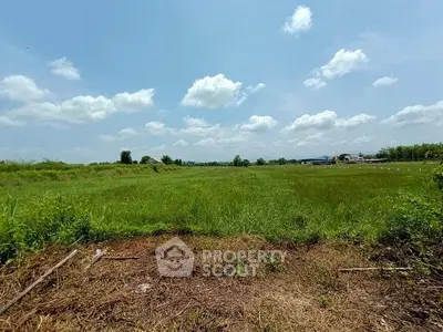 Expansive green field under a bright blue sky, perfect for development opportunities.