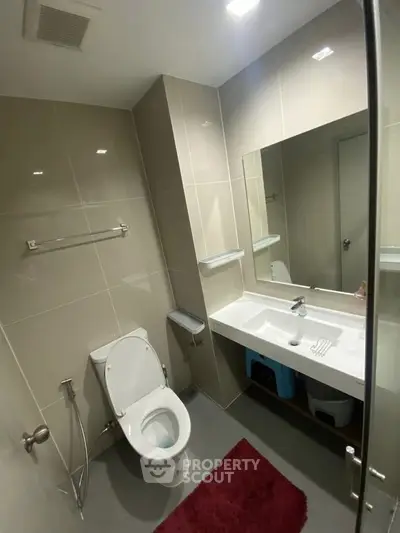Modern bathroom with sleek fixtures and large mirror in contemporary apartment.