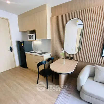 Modern studio apartment with sleek kitchen and cozy living area, featuring stylish wood paneling and contemporary furniture.