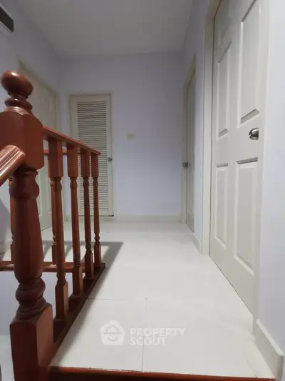 Spacious hallway with wooden railing and multiple doors in a modern home.