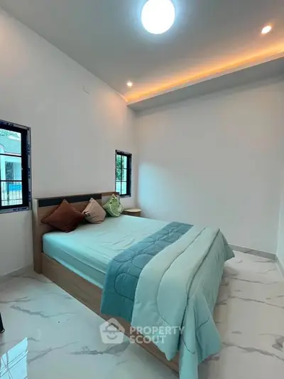 Spacious bedroom with modern decor and natural light, featuring a comfortable bed and stylish flooring.