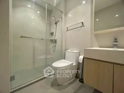 Modern bathroom with glass shower and sleek fixtures in contemporary apartment.