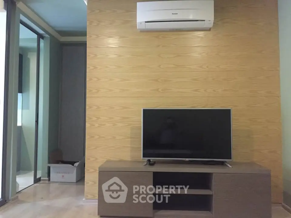 Modern living room with sleek TV setup and air conditioning unit, featuring stylish wood paneling.