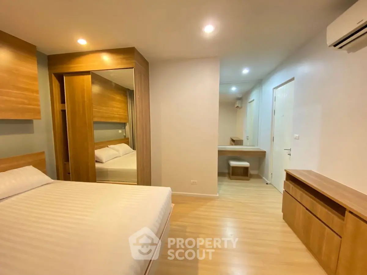 Modern bedroom with wooden furniture and cozy lighting, featuring a spacious layout and stylish design.