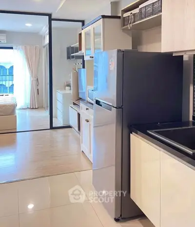 Modern kitchen with sleek appliances and open layout leading to a cozy bedroom.