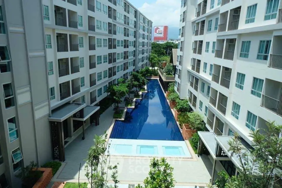 Modern apartment complex with central swimming pool and lush greenery.