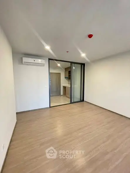 Spacious modern living room with wooden flooring and glass sliding doors to kitchen.