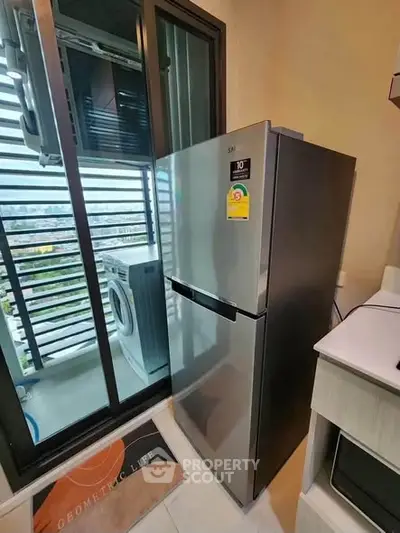 Modern kitchen with stainless steel fridge and balcony view, featuring washing machine and sleek design.