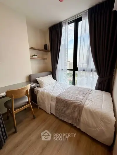Cozy bedroom with large window offering city view, featuring a comfortable bed and modern decor.