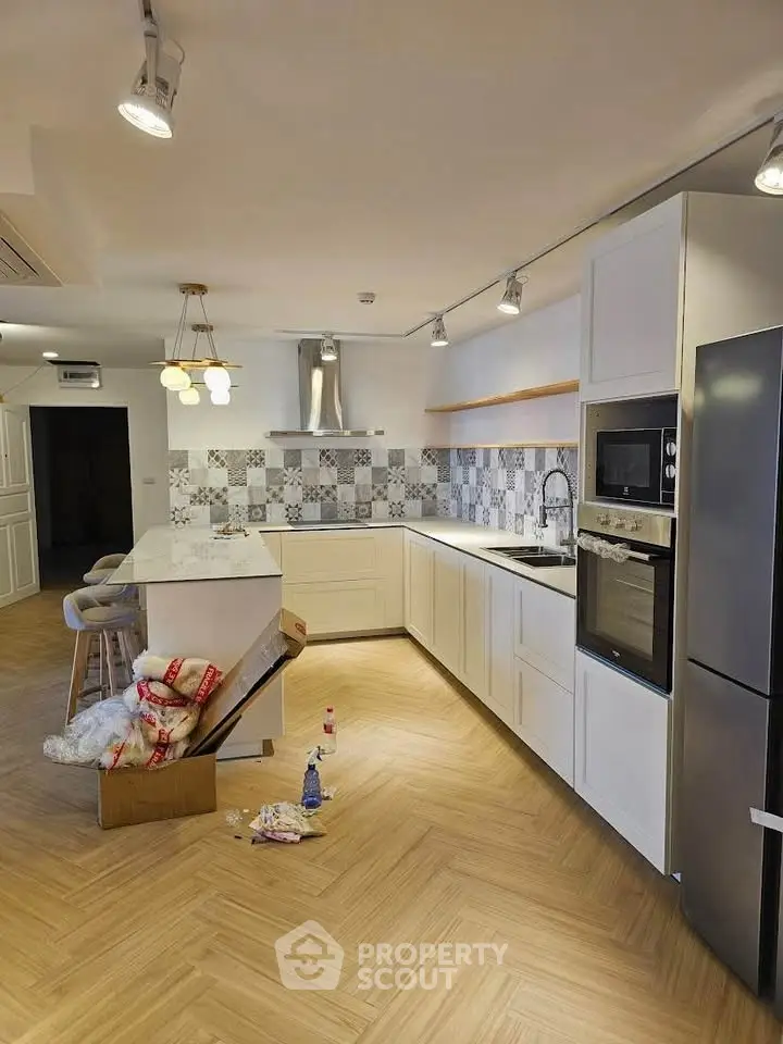 Modern kitchen with sleek appliances and stylish backsplash in open layout.