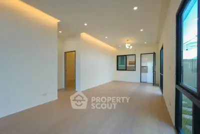 Spacious modern living room with wooden flooring and large windows for natural light.