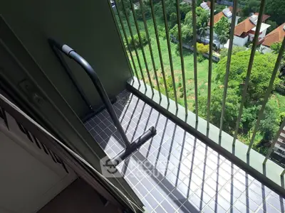 High-rise balcony with scenic green view and safety railing, perfect for relaxation.