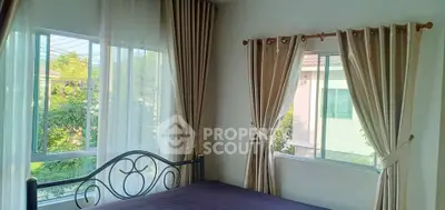 Bright bedroom with large windows and elegant curtains in a cozy home.