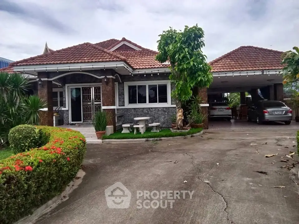 Charming single-story home with red-tiled roof, lush garden, and spacious driveway.