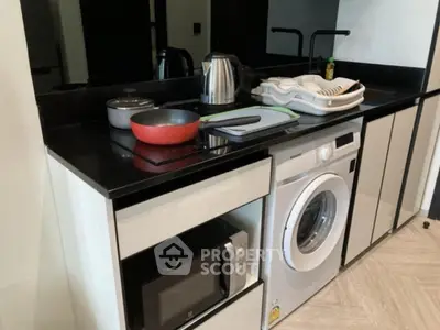 Modern kitchen with sleek appliances including washing machine and microwave