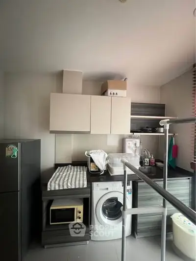 Modern kitchen with washing machine and microwave in compact layout