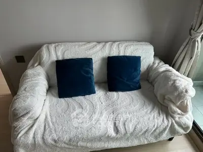 Cozy living room with plush white sofa and blue cushions, perfect for relaxation.