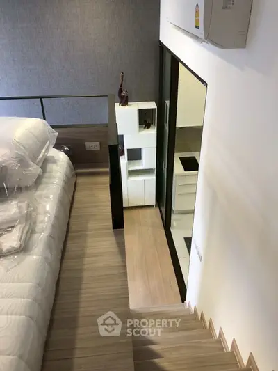 Modern loft bedroom with stylish decor and wooden flooring, featuring a cozy elevated sleeping area.