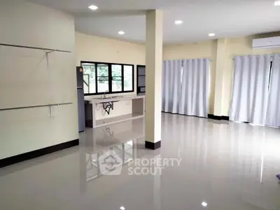 Spacious open-plan living area with large windows and modern kitchen setup.