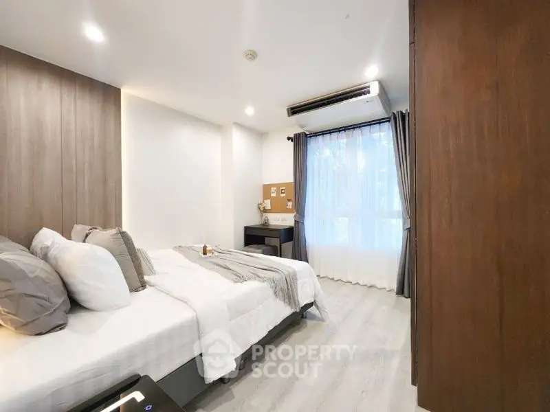 Modern bedroom with stylish decor and natural light through large window.