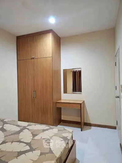 Cozy bedroom with wooden wardrobe and matching vanity, perfect for modern living.