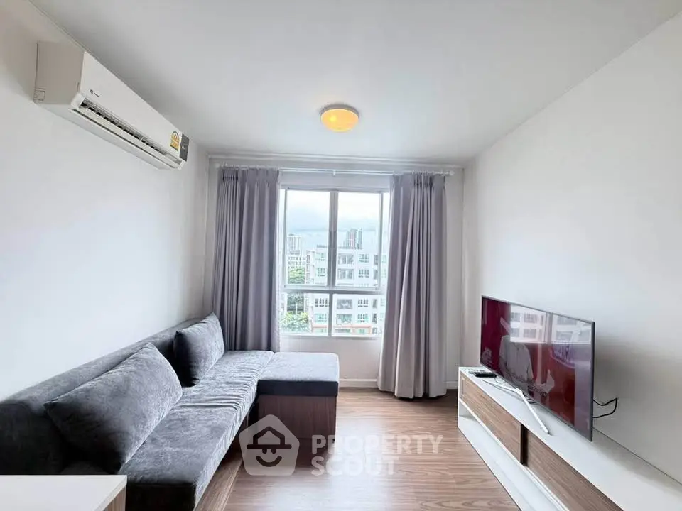Modern living room with sleek furniture and large window offering city views.