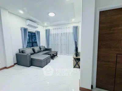 Modern living room with sleek gray sofa and elegant curtains, featuring a minimalist design and bright ambiance.