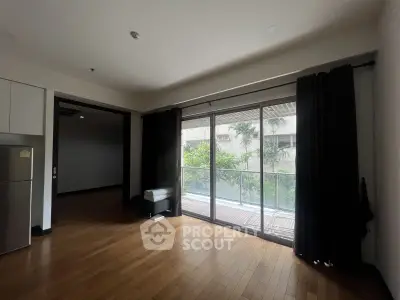 Spacious living room with large windows and balcony view, featuring hardwood floors and modern design.