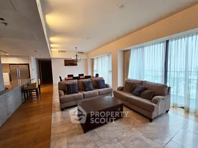 Spacious modern living room with elegant furniture and large windows offering natural light.