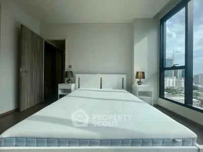 Spacious bedroom with large window offering stunning city views, featuring modern furniture and ample natural light.