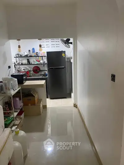 Compact kitchen with modern fridge and open shelving for efficient storage.