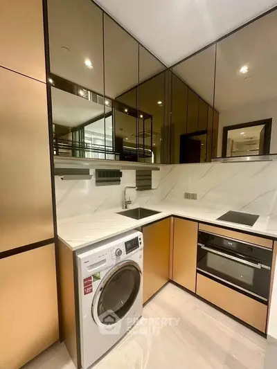 Modern kitchen with sleek cabinetry, built-in oven, and washing machine in a stylish apartment.