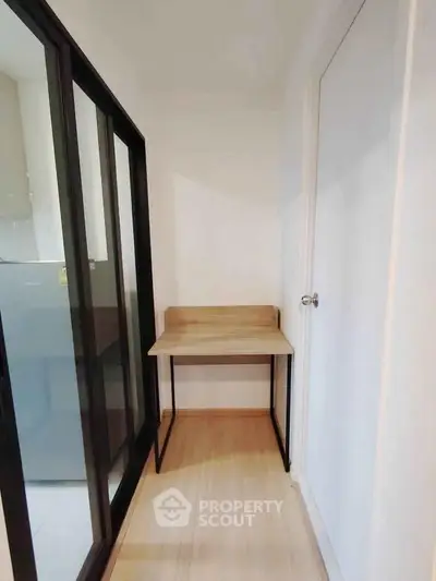 Compact study nook with wooden desk and sliding glass doors in modern apartment