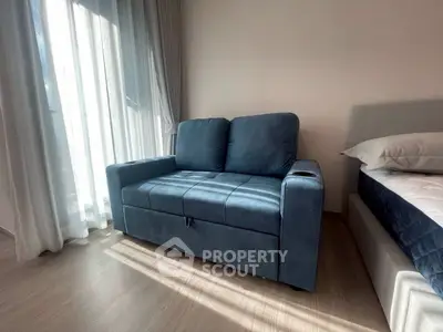 Cozy living room with a stylish blue sofa and natural light from large windows.