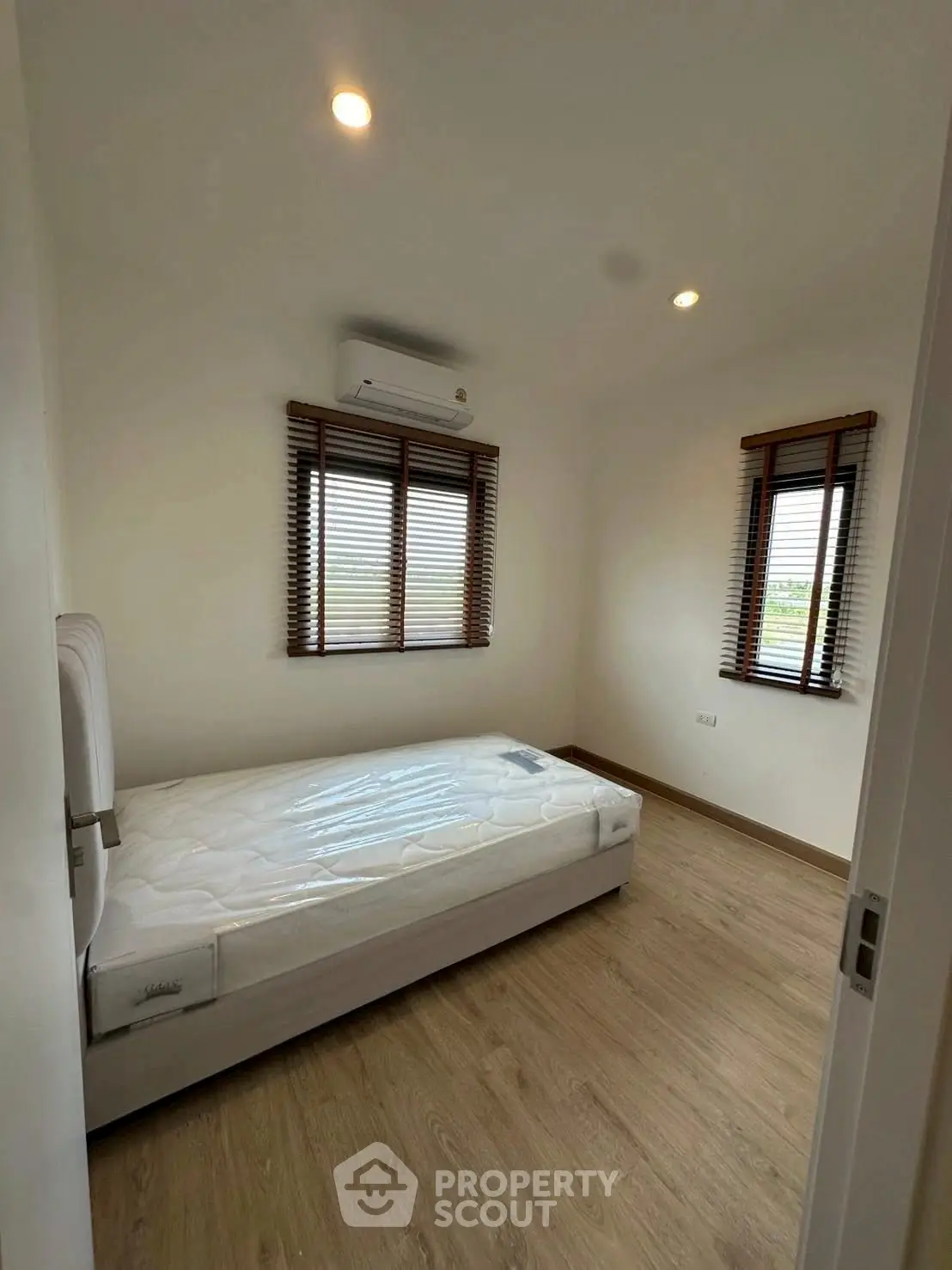 Cozy bedroom with natural light and minimalist design, featuring a single bed and wooden flooring.