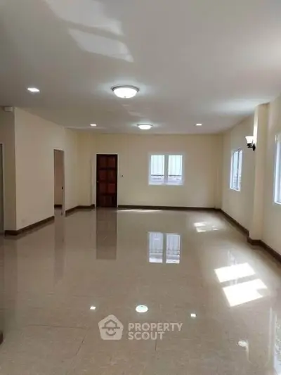 Spacious empty living room with glossy tiled floors and ample natural light.