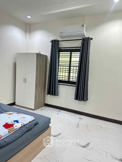 Modern bedroom with air conditioning and stylish decor, featuring a cozy bed and sleek wardrobe.