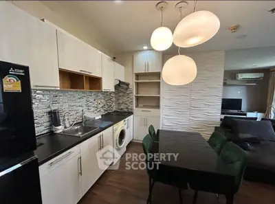 Modern kitchen with sleek cabinets, washing machine, and stylish dining area in open layout apartment.