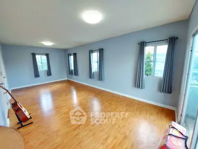 Spacious empty room with wooden flooring and large windows, ideal for customization.