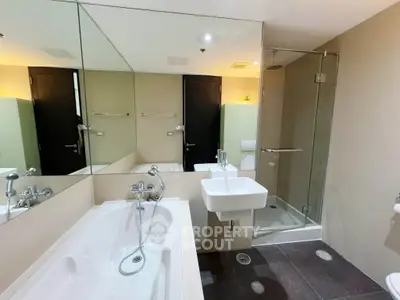 Modern bathroom with bathtub and glass shower enclosure in a stylish apartment.