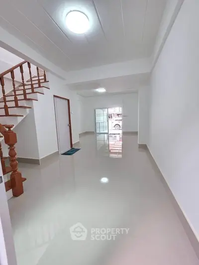 Spacious modern hallway with glossy floors and wooden staircase in a contemporary home.